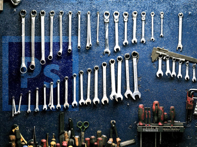 tools hanging on a wall with the photoshop logo in background