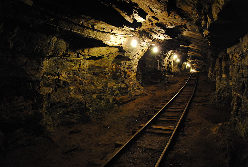 make money with photography as a beginner - image of a mine with lights hanging from the ceiling and a railroad track going off into the distance